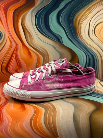 Pink sneaker on a colorful, wavy-patterned surface